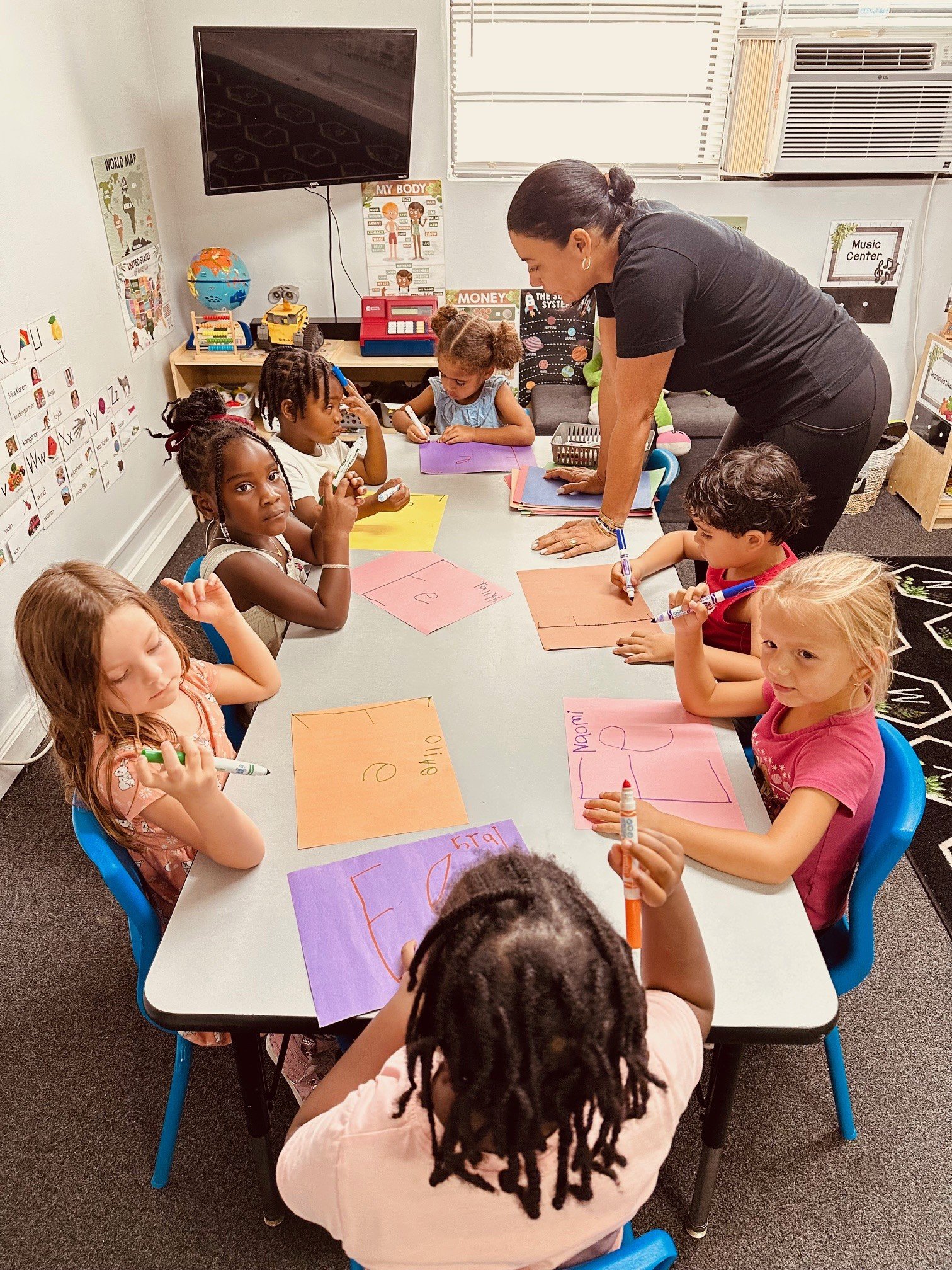 Teacher helping preschoolers with an art activity